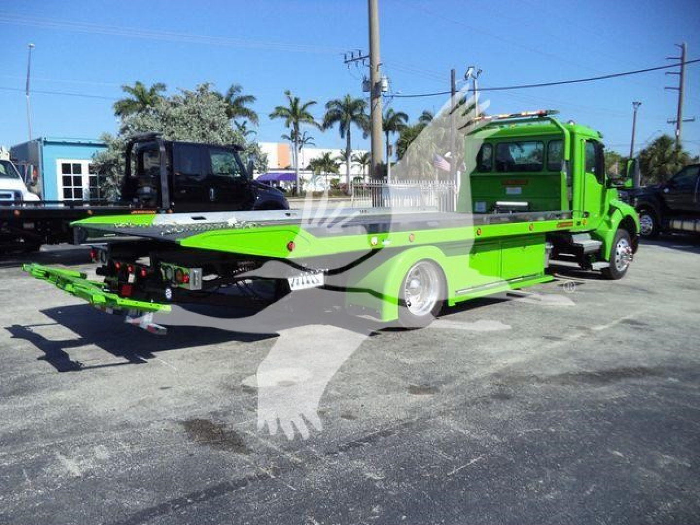 Kenworth T280 rollback tow truck in bright green with flatbed extended, side view showing winch area and dual rear wheels.