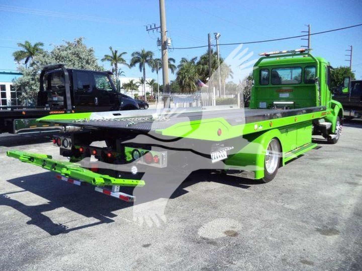 Green tow truck with a flatbed rollback trailer viewed from rear-left side, KW1STEPSIDE stock number visible, bright daylight.