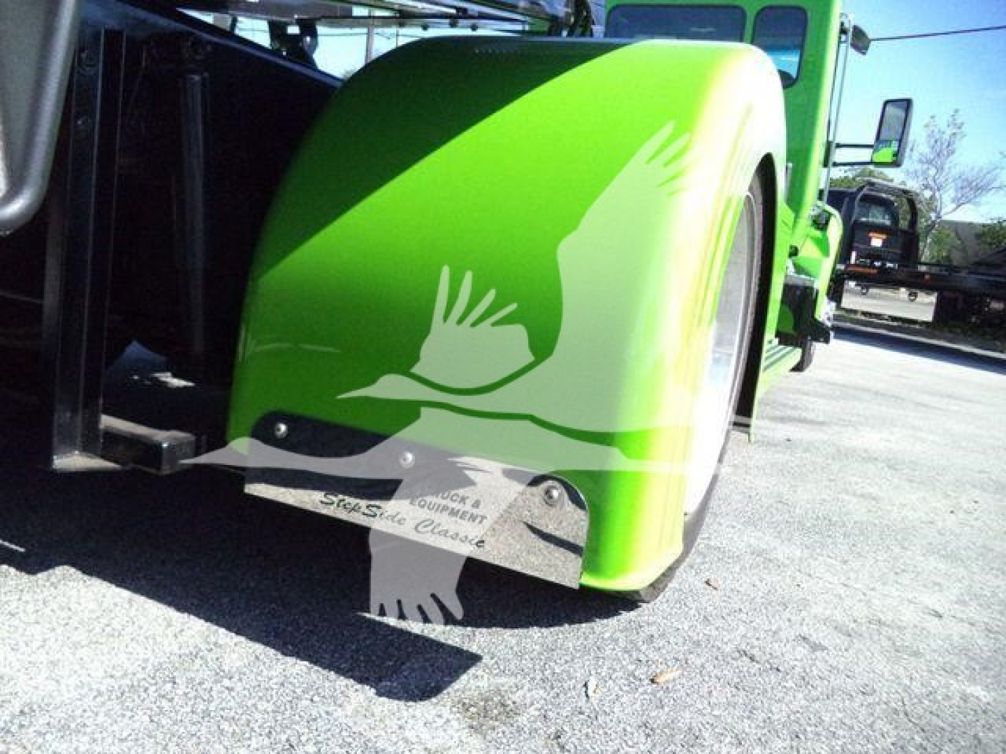 Kenworth T280 rollback truck with bright green paint; close-up of front wheel well and lower panel with graphics.