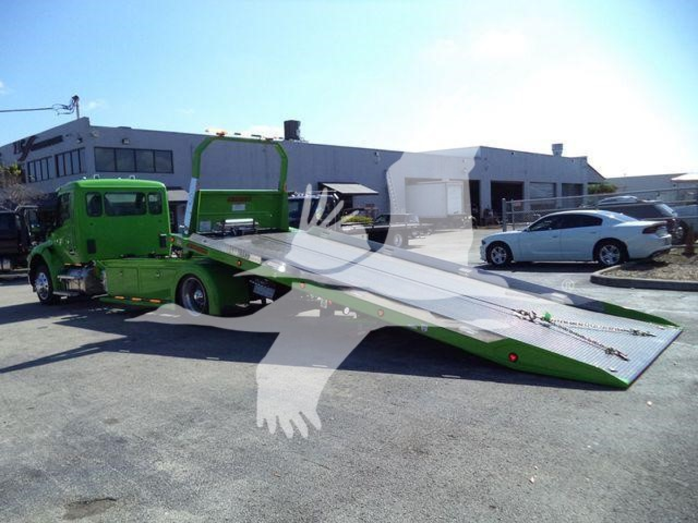 Kenworth T280 rollback tow truck with a lowered green ramp bed and a green tow truck unit, in a dealership lot.
