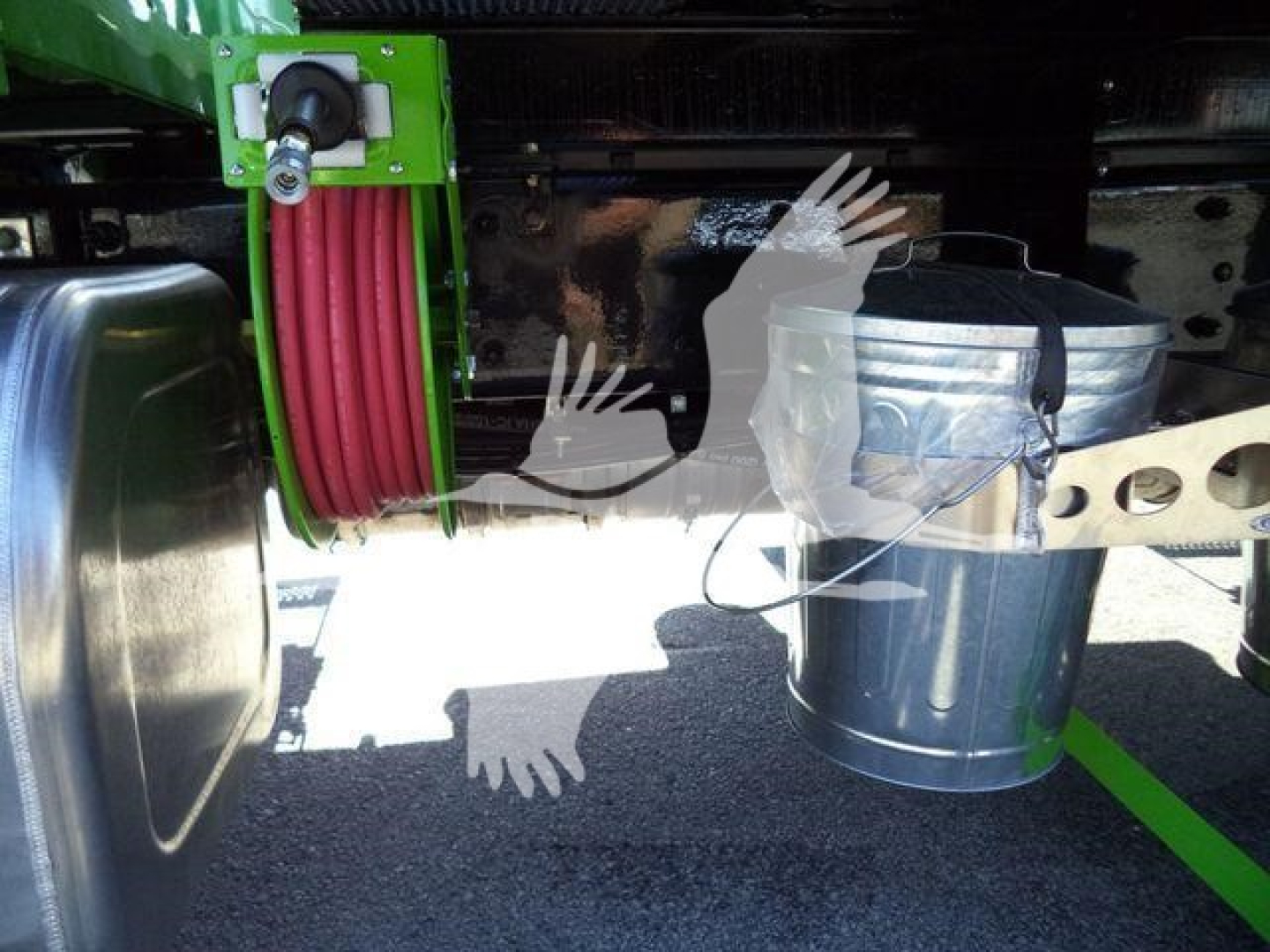 Kenworth T280 rollback truck undercarriage showing coiled hose reel and metal bucket attached to chassis