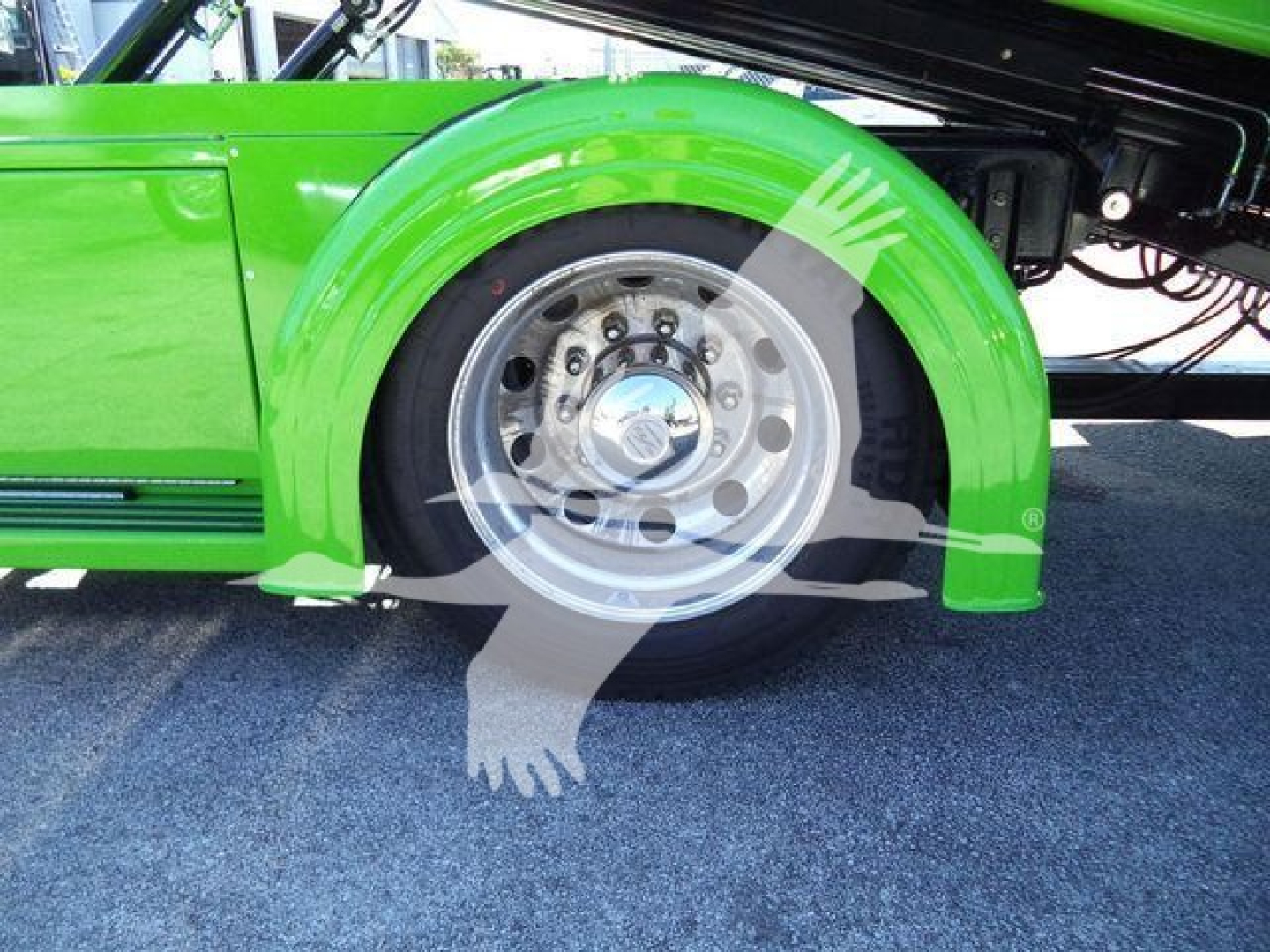 Kenworth T280 rollback truck wheel and fender, bright green paint with chrome hubcap and wheel, hydraulic lines visible in background.