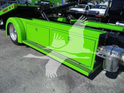 Kenworth T280 rollback truck side view showing bright green storage compartments and chrome fuel tank. Side panels and wheel visible.