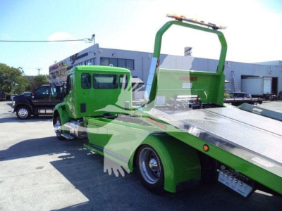 Kenworth T280 rollback carrier with bright green cab and loaded flatbed; side view showing wheel, chrome fuel tanks, and roll-back bed with winch pad.