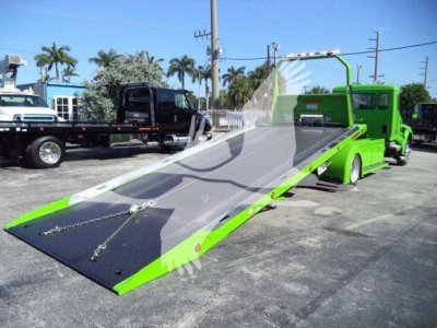 Kenworth T280 rollback wrecker bed in open position showing bright green body and clear ramp surface.