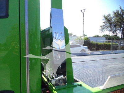 Kenworth rollback truck component showing green chassis and metal platform with hydraulic equipment.
