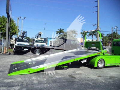 Kenworth T280 rollback wrecker with bright green ramp bed and gray-tinted cab in a dealership lot.