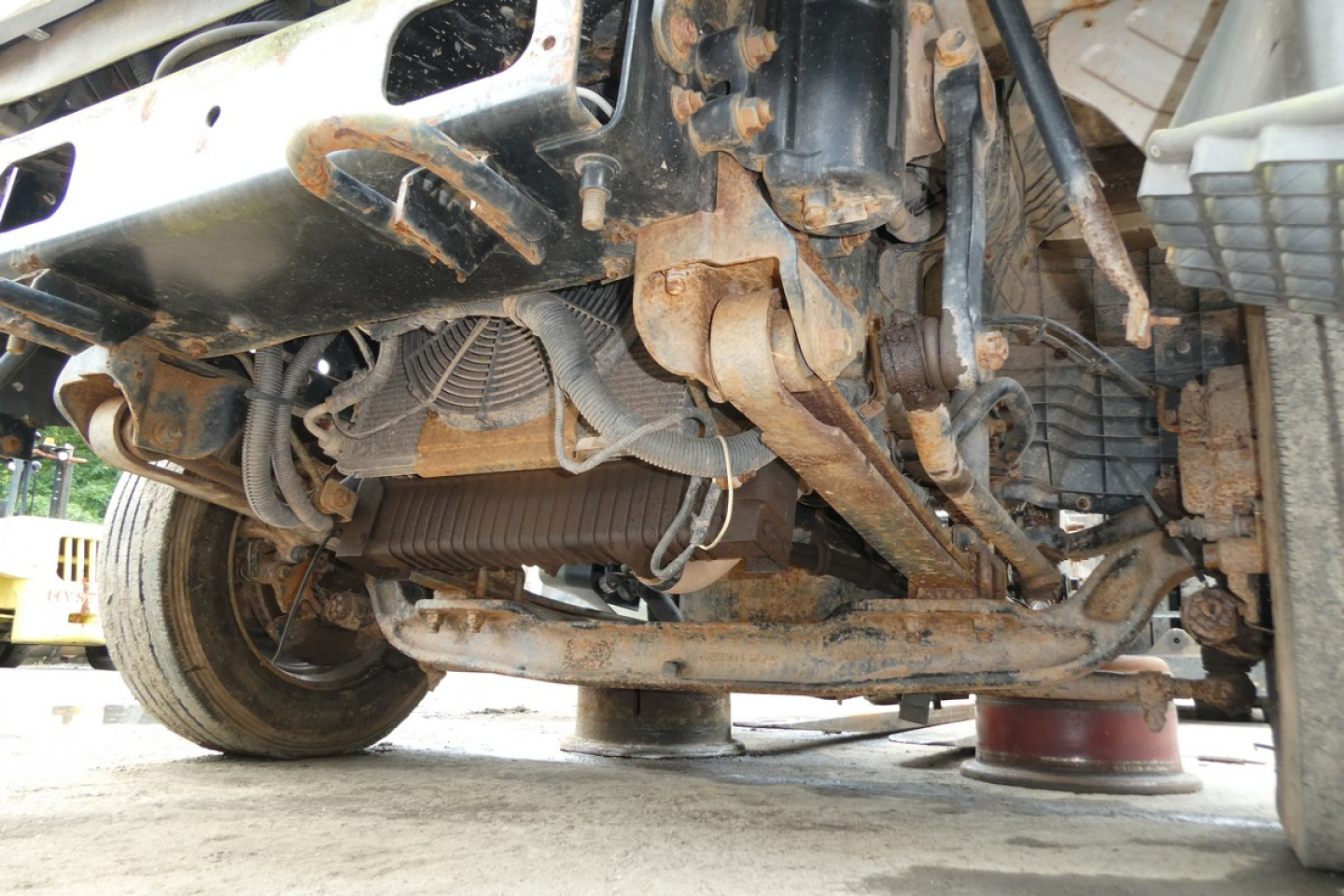 Underneath view of a 2006 Ford LCF chassis showing exposed suspension components and drivetrain with rust and dirt buildup.