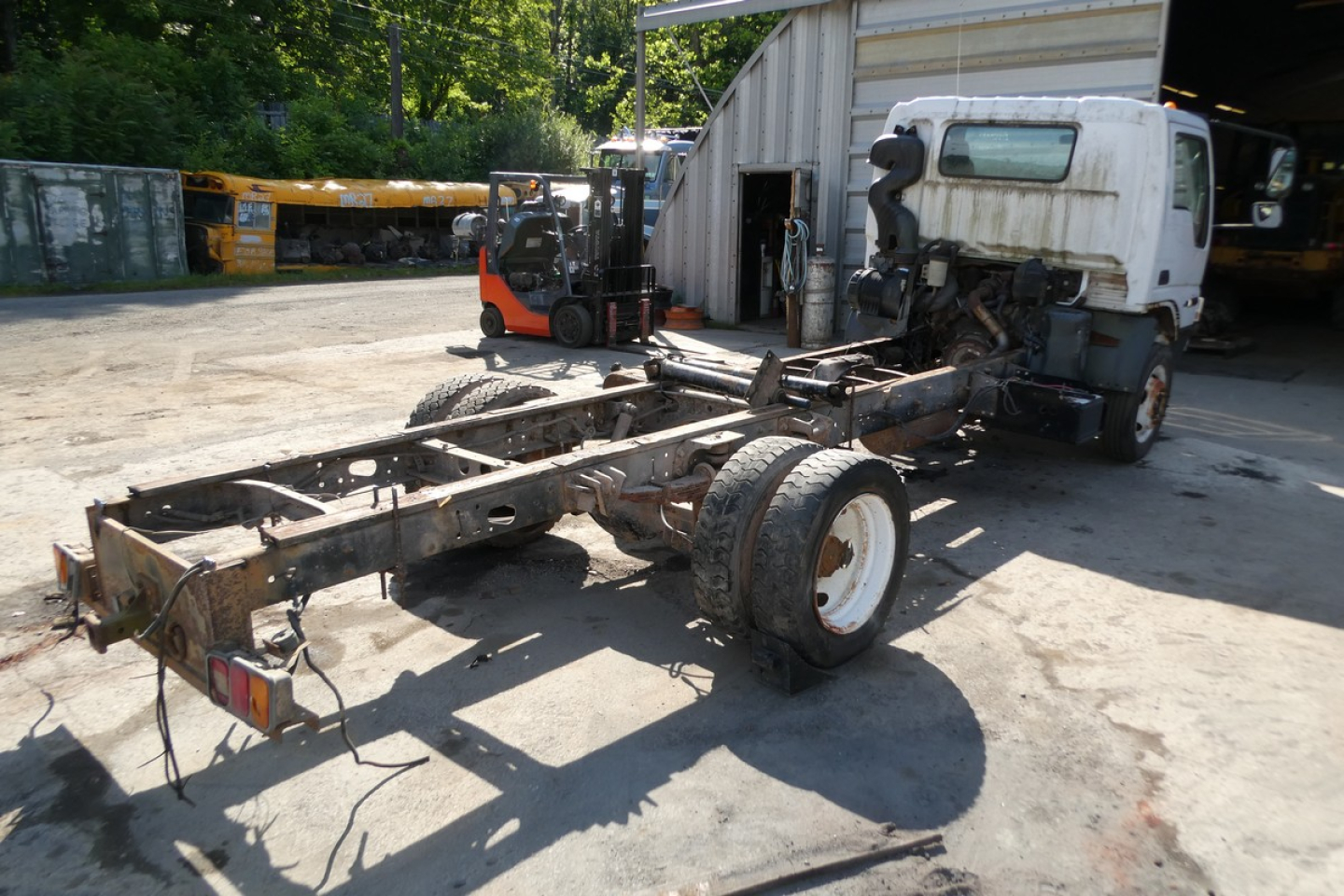 Ford LCF cab and chassis frame with cab removed, single rear axle, white cab, in a yard.