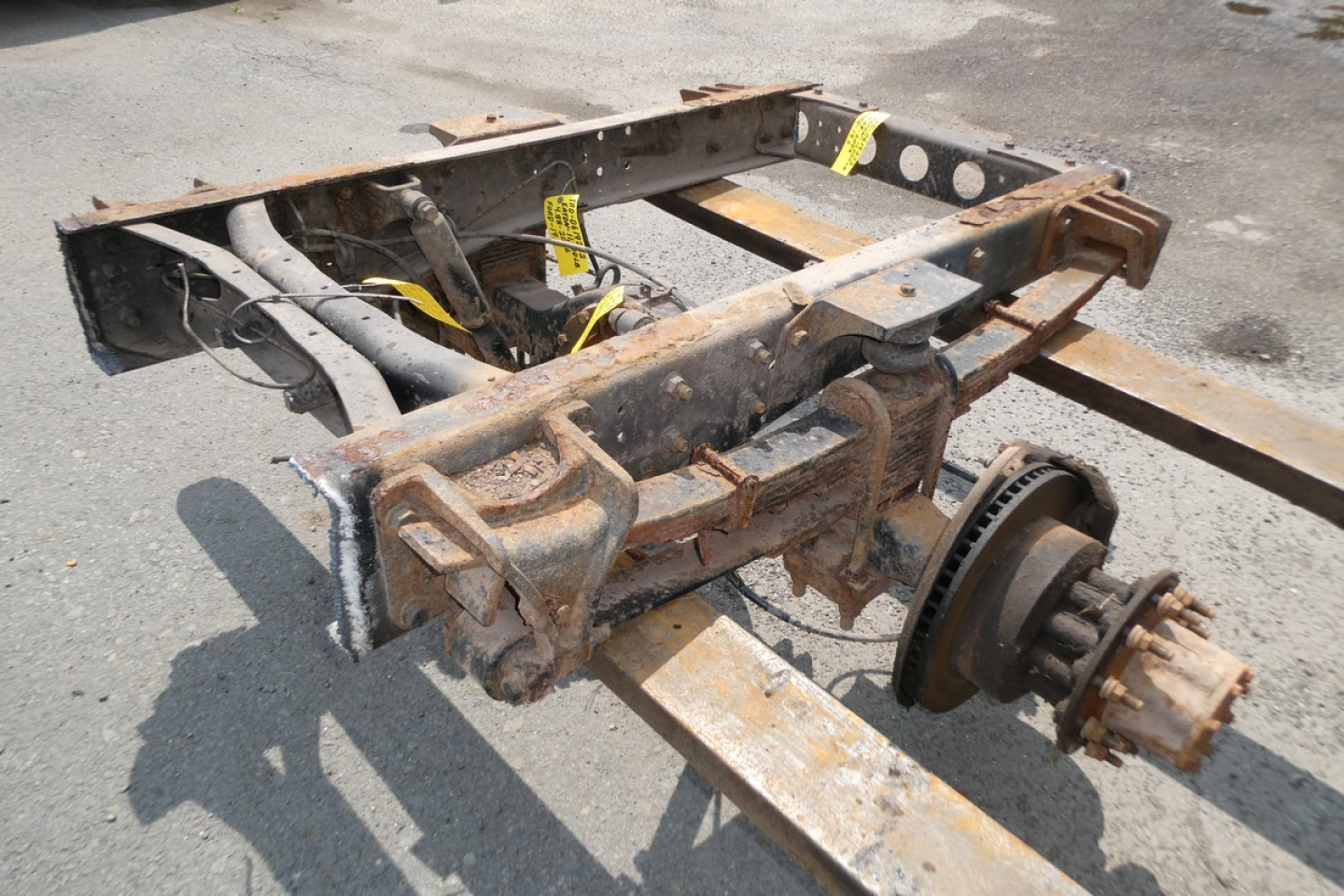Frame and drivetrain subframe with rusted components and a wheel hub on a truck chassis.