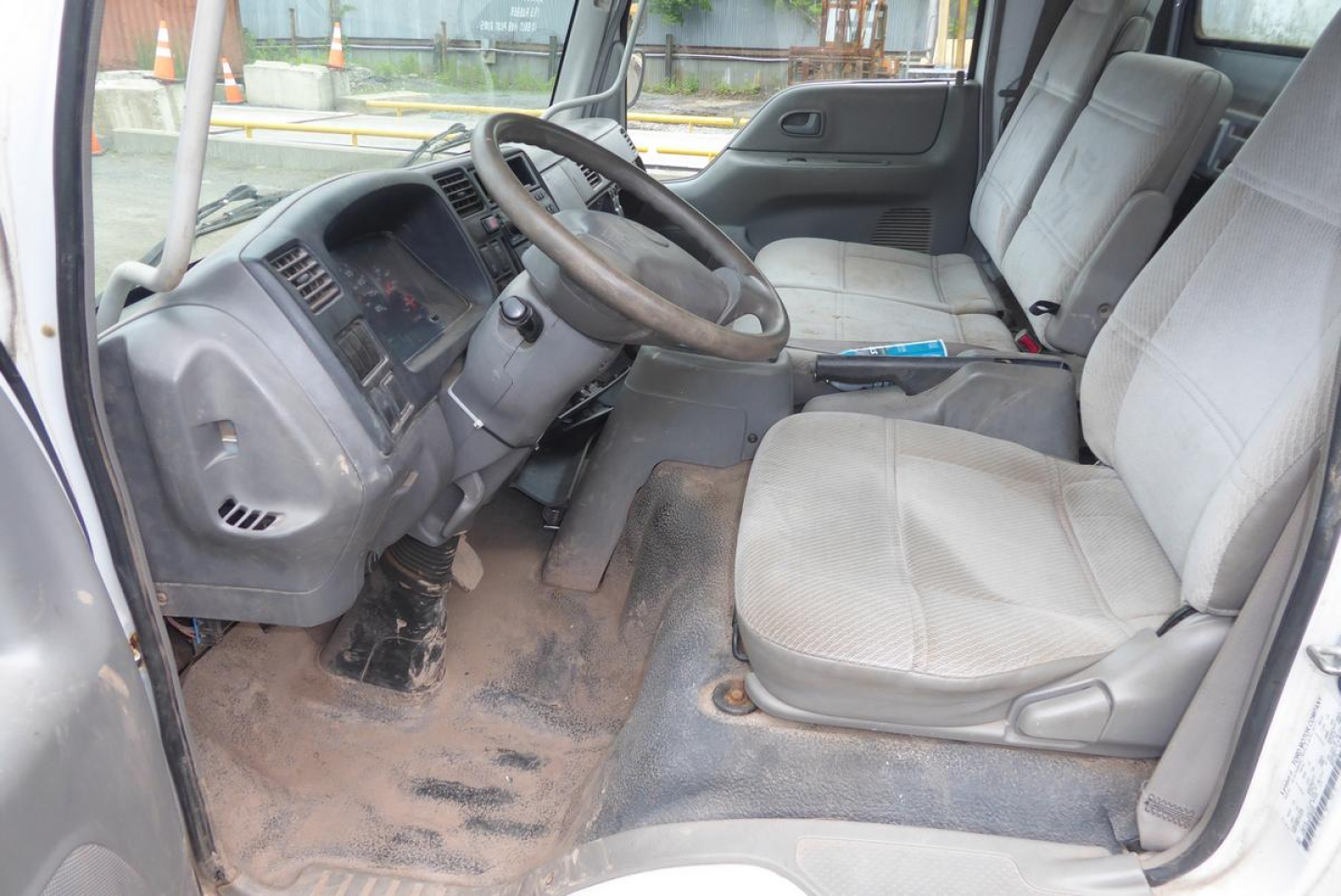 Ford LCF cab and chassis interior showing steering wheel, dash, and front seats with floor mat and dirt.