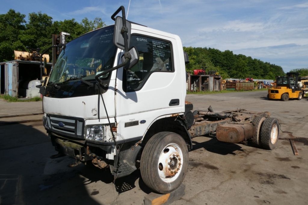 Ford LCF cab and chassis truck in a yard, front-left view with exposed chassis rear, white cab, mid-migeon