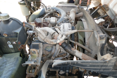 Ford LCF engine bay showing alternator, coolant reservoir, radiator, hoses, and engine components in a cab-and-chassis truck.