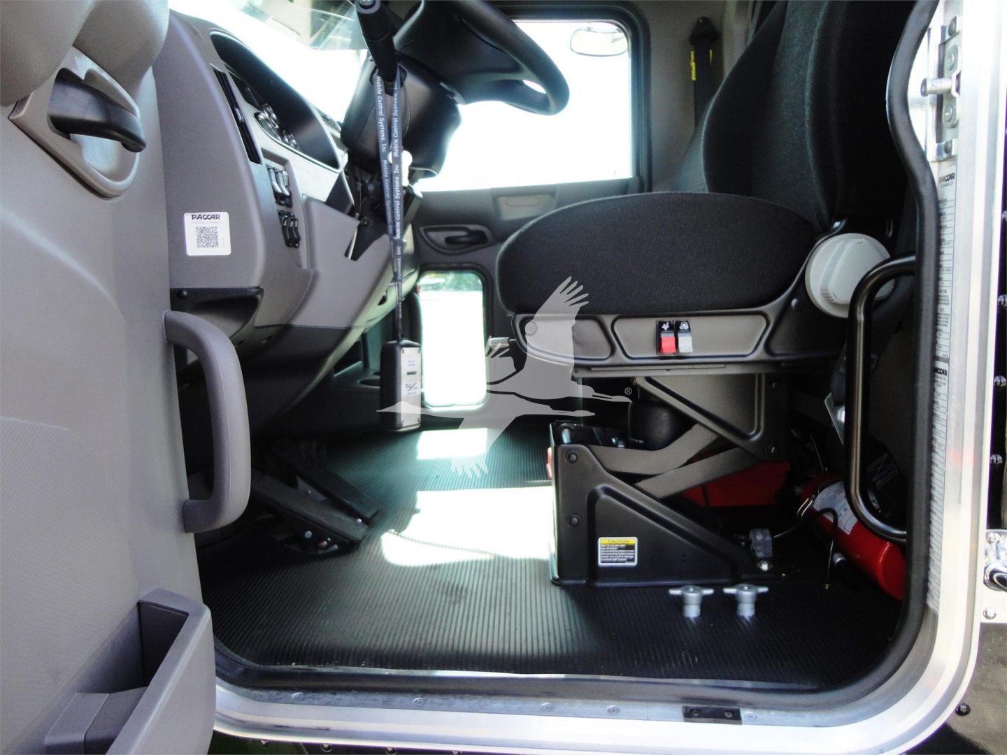 Peterbilt 337 cab interior with driver's seat, dashboard, and entry area; ground surface with rollover recovery equipment visible near floor.