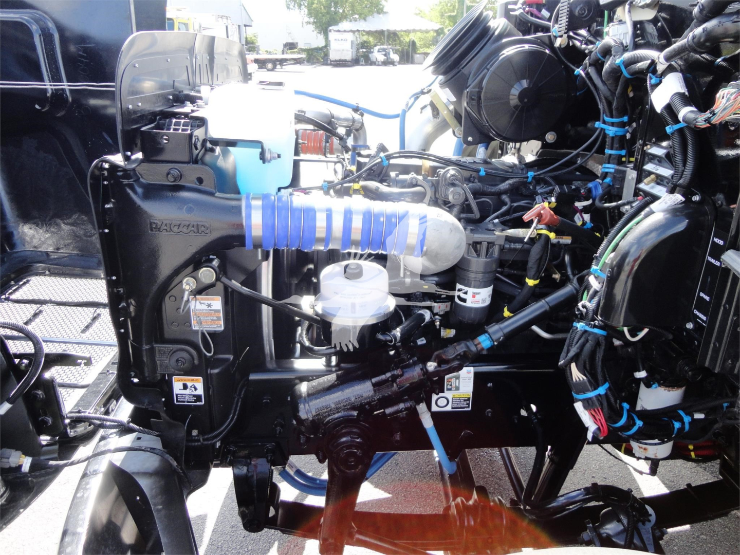 Peterbilt 337 engine bay showing air intake, hoses, wiring harnesses, and coolant reservoir in a rollback truck.