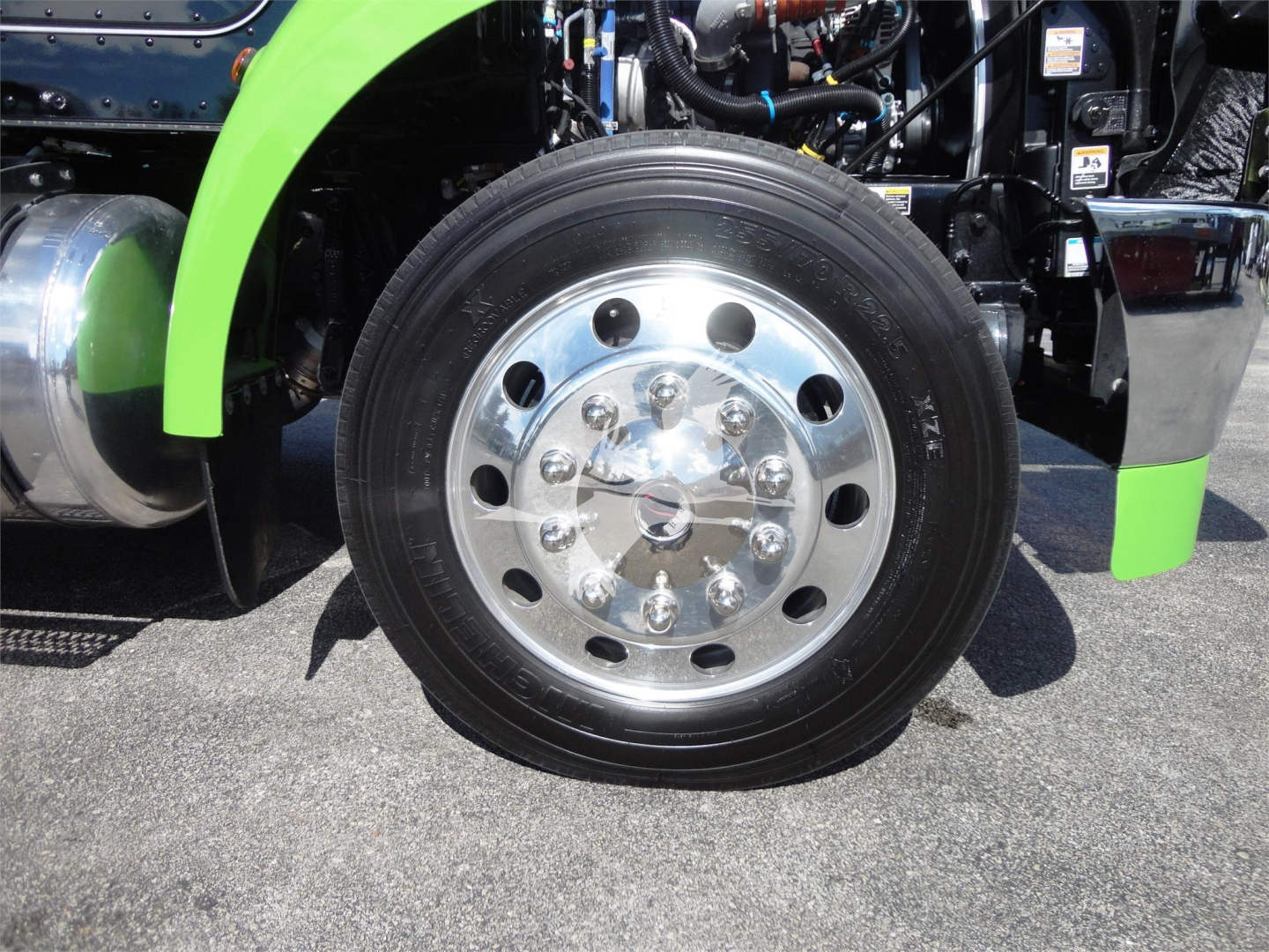 Peterbilt 337 front wheel showing chrome wheel with lug nuts and green fender in service bay