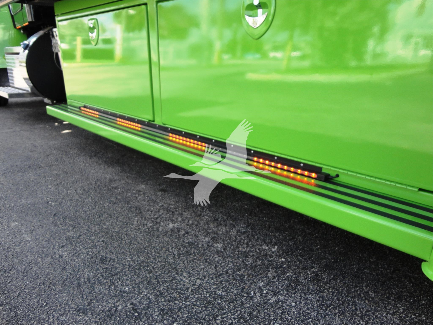 Side view of a bright green Peterbilt 337 rollback truck with illuminated underbody LED step lights along the lower side panel.