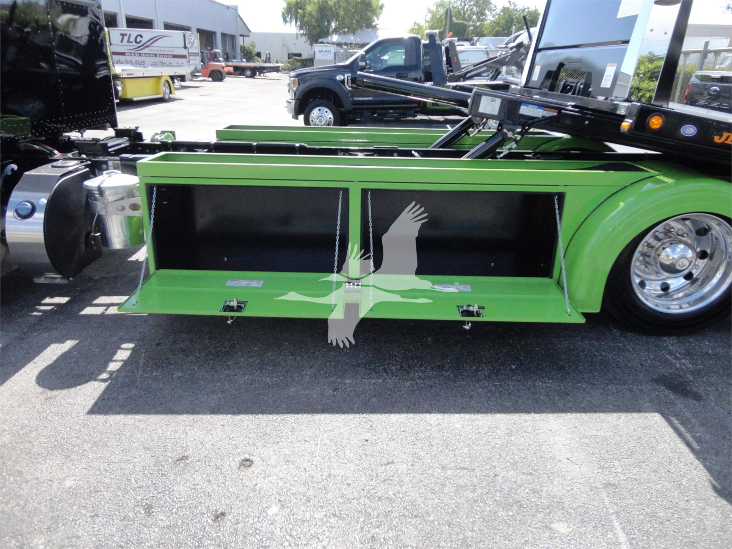 Peterbilt 337 rollback truck side view showing green toolbox compartments and chrome wheels.