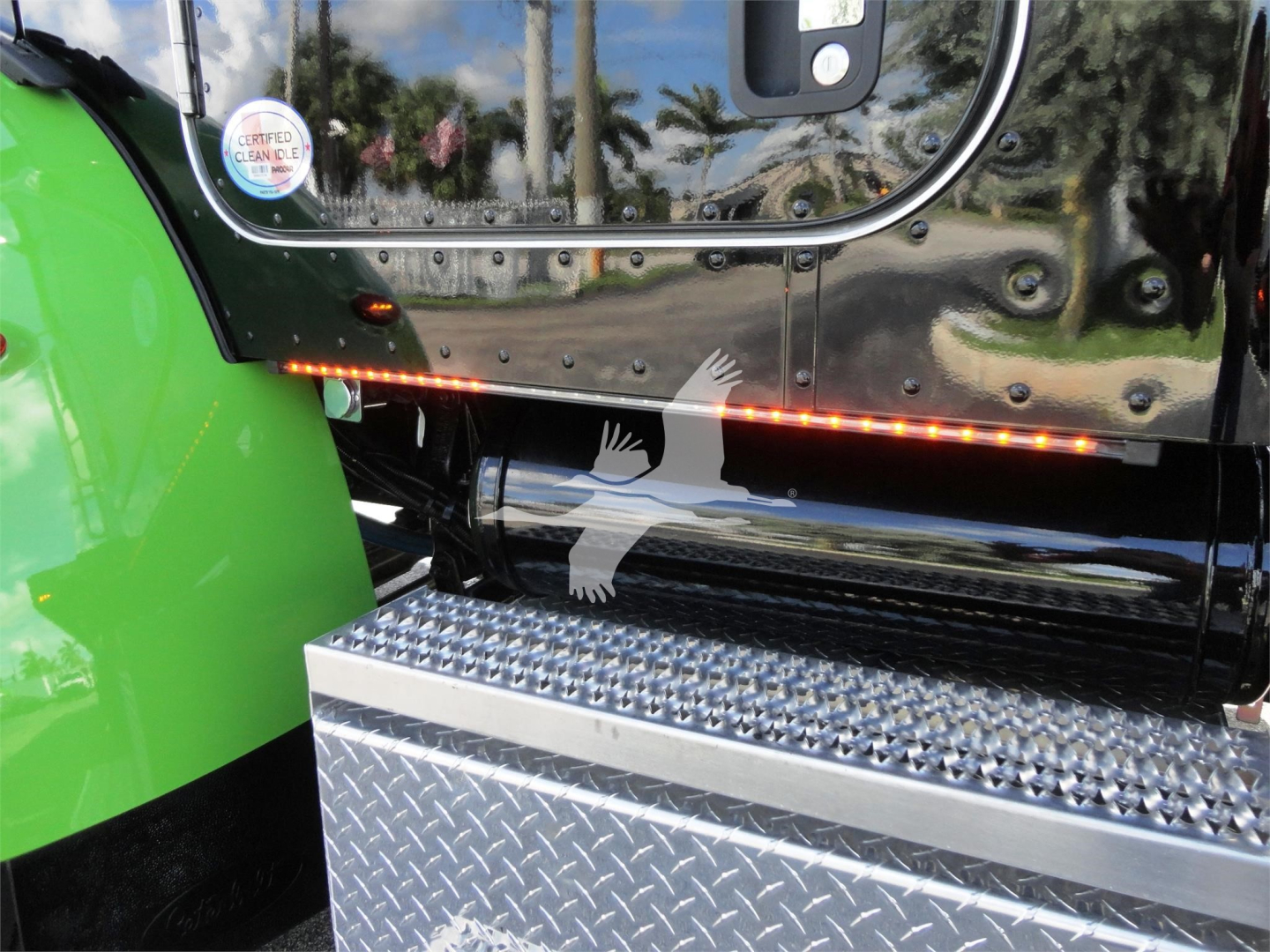 Peterbilt 337 side step with chrome fuel tank, green fender, and diamond plate step; visible red LED strip along undercab area.