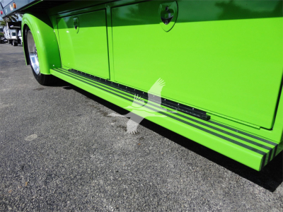 Side view of a bright green Peterbilt 337 rollback truck showing lower side rail and storage compartments.