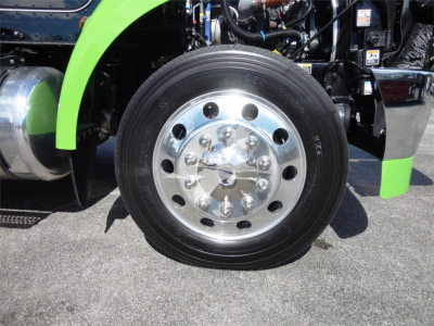 Peterbilt 337 front wheel showing chrome wheel with lug nuts and green fender in service bay