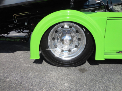 Green Peterbilt 337 rollback truck front wheel and fender with chrome wheel and tire visible