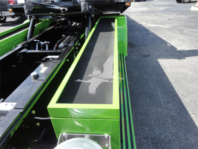 Green Peterbilt 337 rollback truck showing fuel and hydraulic components and a long deck with textured black stepping surface.