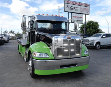 Peterbilt 337 rollback truck in black and bright green color scheme, front view with chrome grille and green lower bumper.