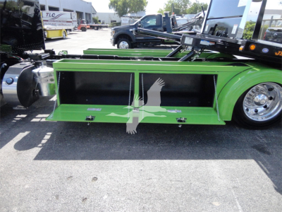 Peterbilt 337 rollback truck side view showing green toolbox compartments and chrome wheels.