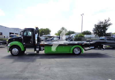 2022 Peterbilt 337 rollback tow truck side view showing green and black color scheme with operator cabin and flatbed.