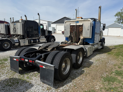 Truck chassis and cab of a 2020 Peterbilt 389 conventional sleeper showing dual rear axles and rear underride guards.