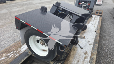 Pitts LB55-18DC lowboy trailer platform with black diamond plate surface, wheel and hydraulic components visible, rear ramps folded, white wheel.