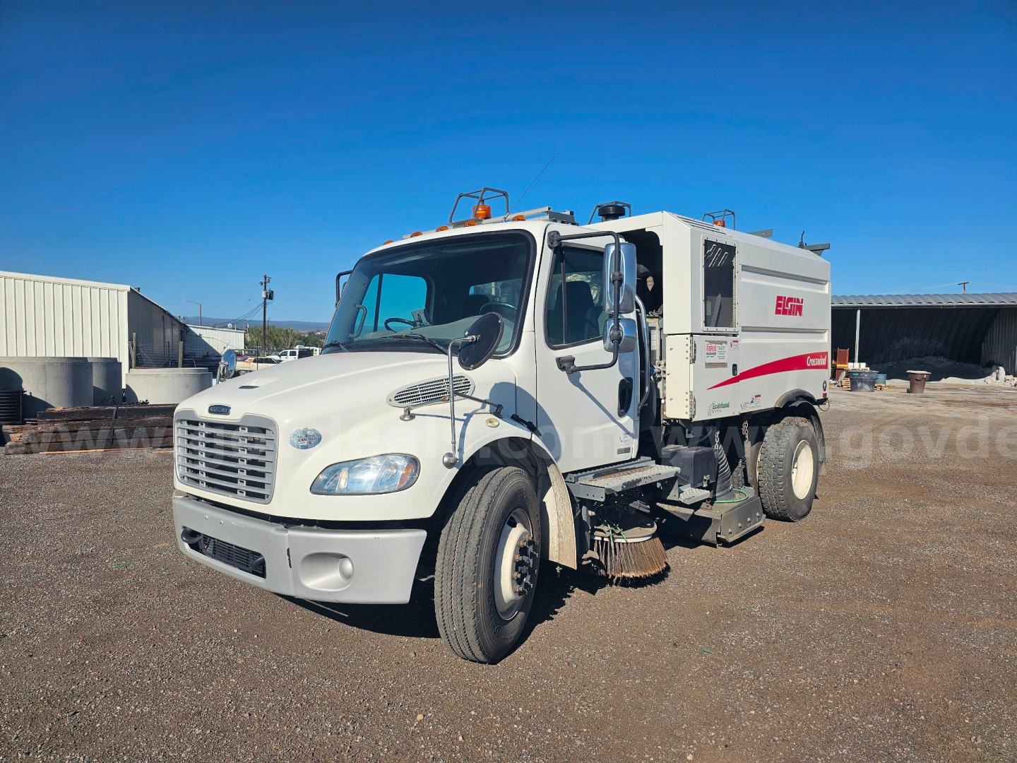 Freightliner M2 106 sweeperside view showing utility body and equipment storage, white cab, swept area undercarriage with brushes, no visible text on side asphalt lot