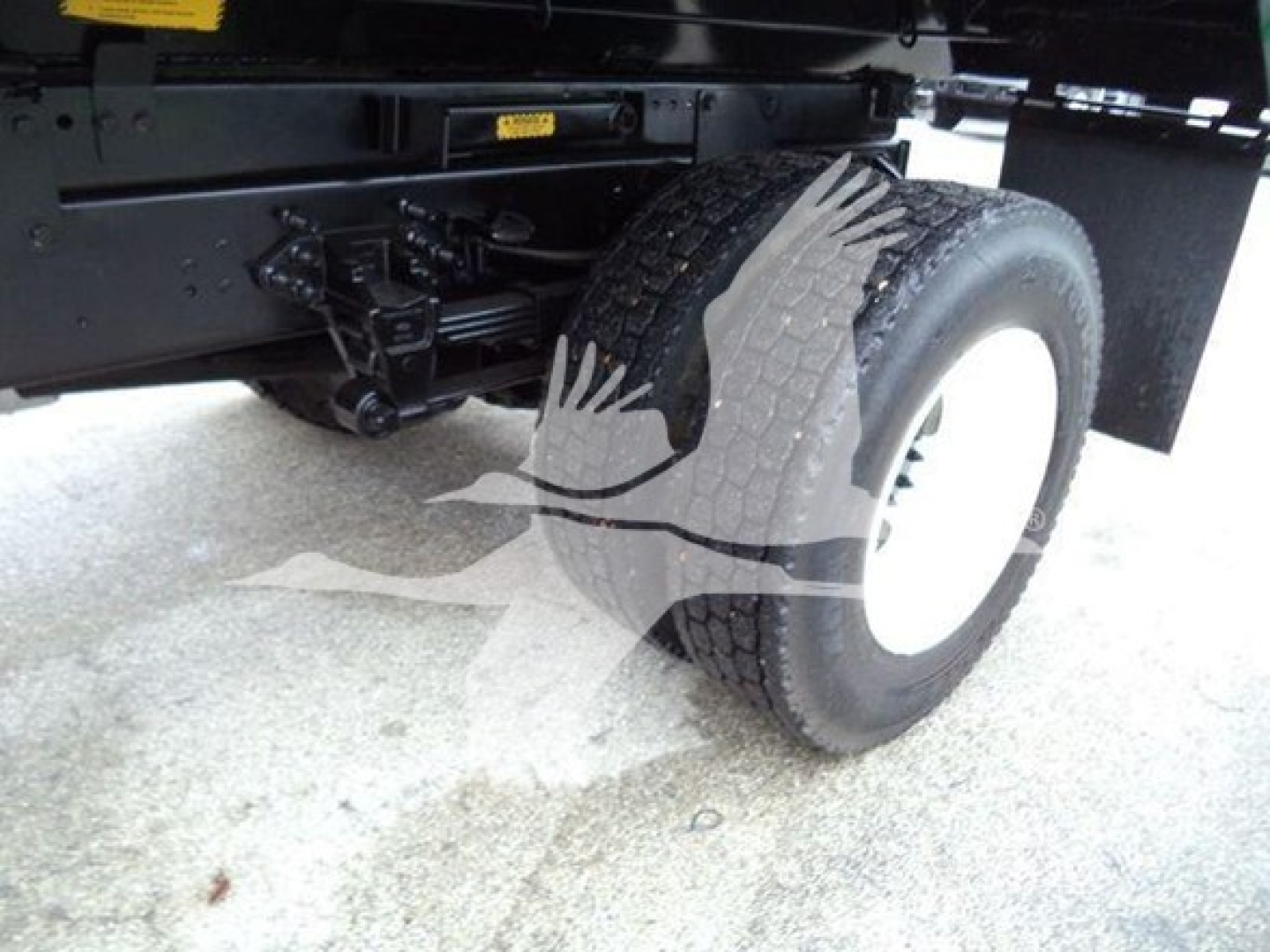 Truck wheel and suspension components under the frame of a 2017 Ford F650 SD dump truck showing rear dual tires and undercarriage.