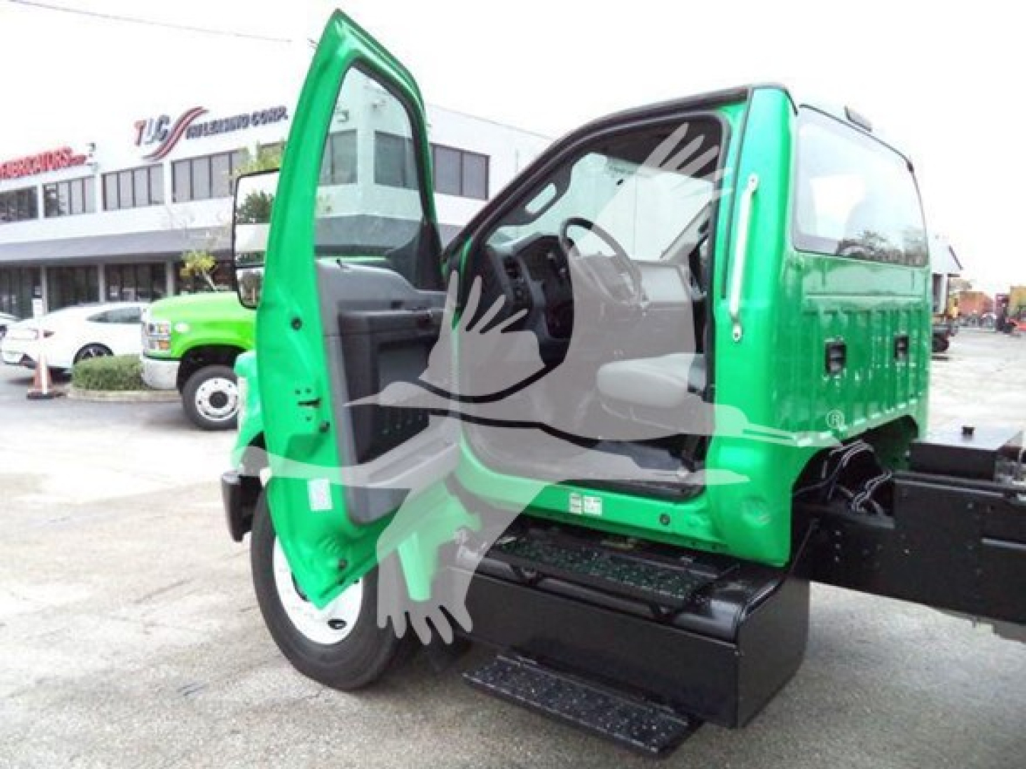 Green Ford F650 cab with door open showing interior and steps on the side. Visible are the cab, chassis, and a side toolbox.