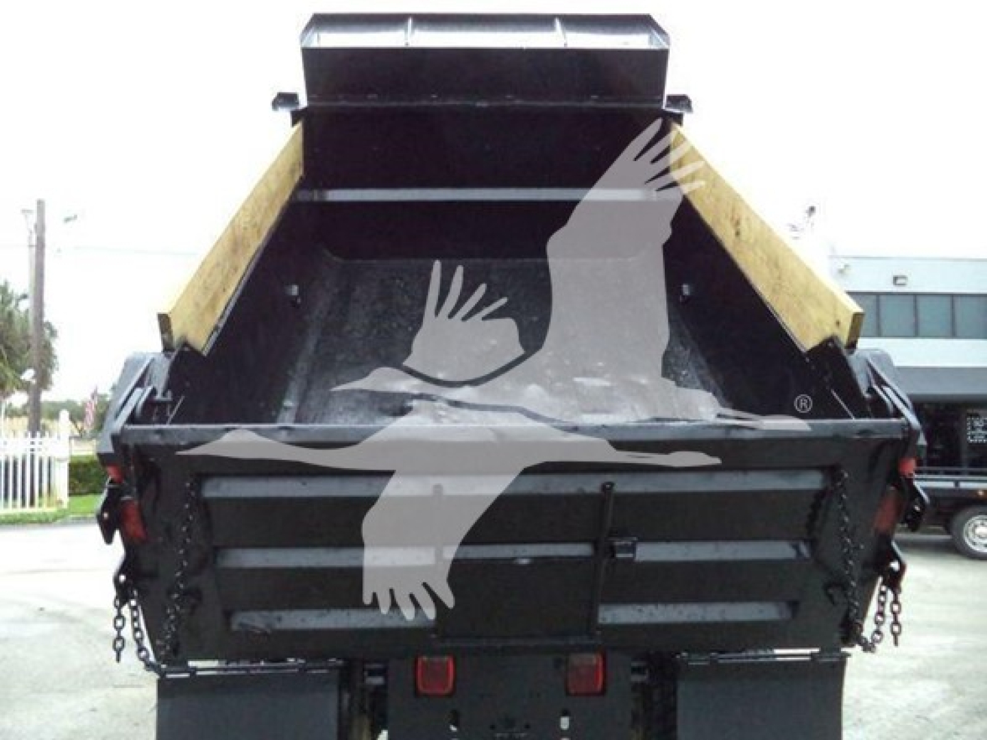 Dump truck bed of a 2017 Ford F650 with black metal sides and yellow dump bed sides; chain hookups visible at rear and hydraulic mechanism in center.