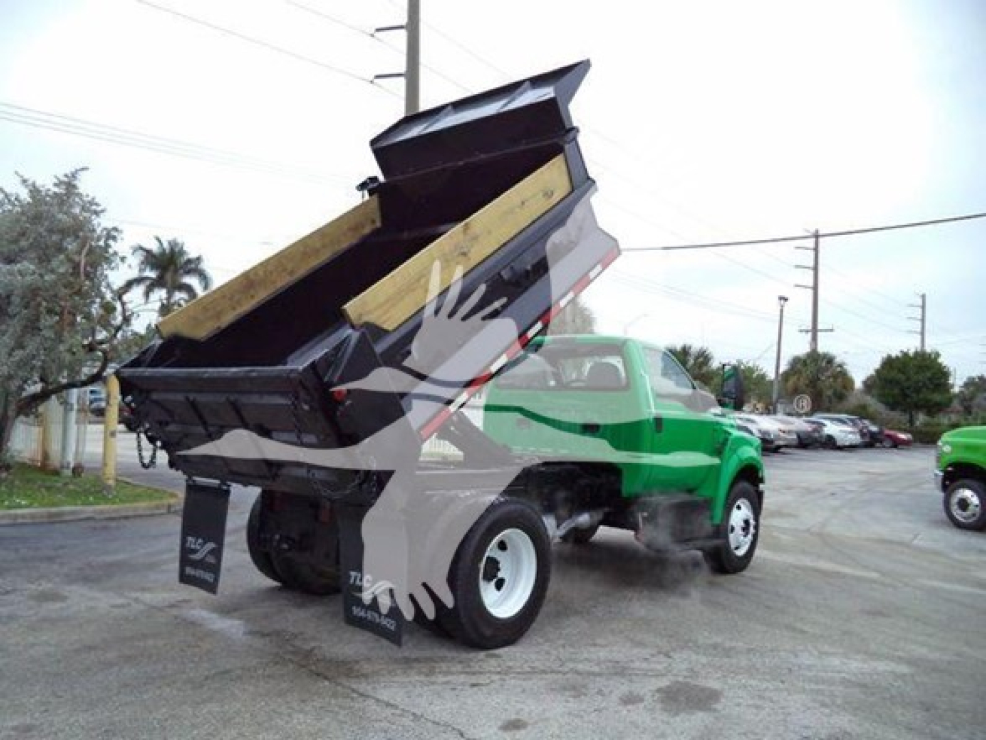 Dump truck 2017 Ford F650 with dump bed raised, green cab, black dump mechanism, front tires and rear dual tires visible.