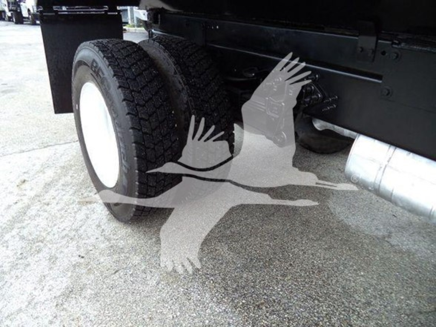 Ford F650 dump truck rear wheel and undercarriage showing dual rear tires and exhaust; side of frame and suspension visible.