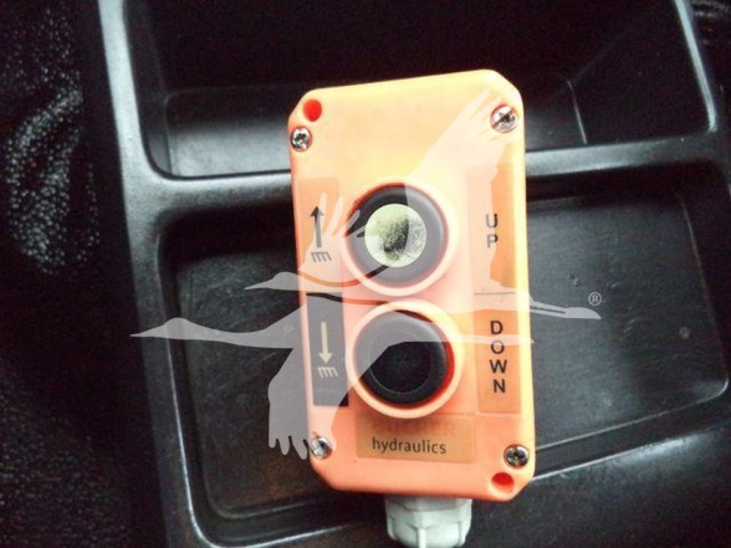 Orange hydraulic control valve with two circular openings labeled up and down, arrows, and text 'hydraulics' on the face.