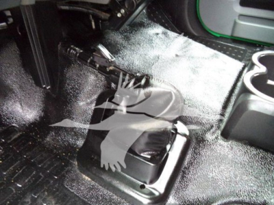 Ford F650 interior floor area around manual transmission shifter boot with rubber matting and cup holders.