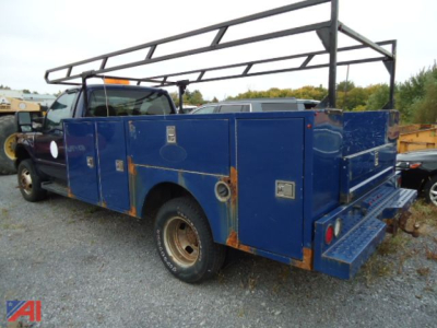 Ford F-350 Super Duty service body with dual rear wheels and roof rack, blue utility trays and storage cabinets, rear bumper, VIN tag area visible.