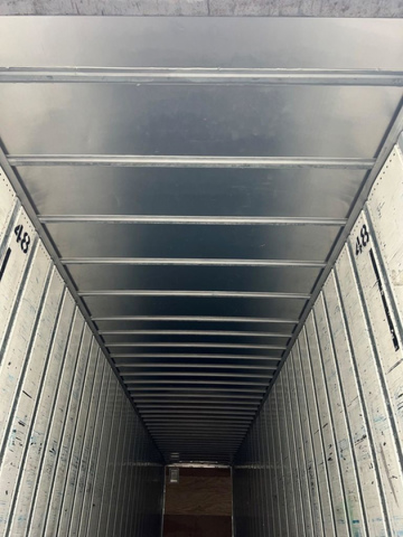Trailer interior view of a cargo van/ trailer with metal side panels and ribbed ceiling showing numbers 448 on both sides.