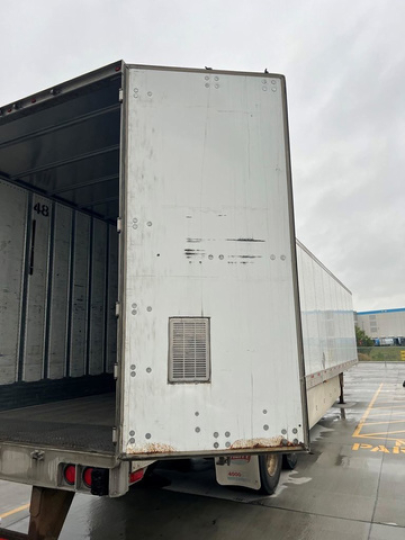 Trailer rear of a 2014 utility van showing open cargo area and rear doors, with riveted aluminum sides and a small vent panel on the left door.