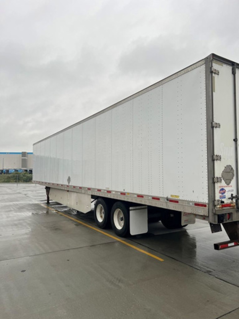 Utility van trailer showing a long white semi-trailer with tandem axles