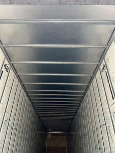 Trailer interior view of a cargo van/ trailer with metal side panels and ribbed ceiling showing numbers 448 on both sides.