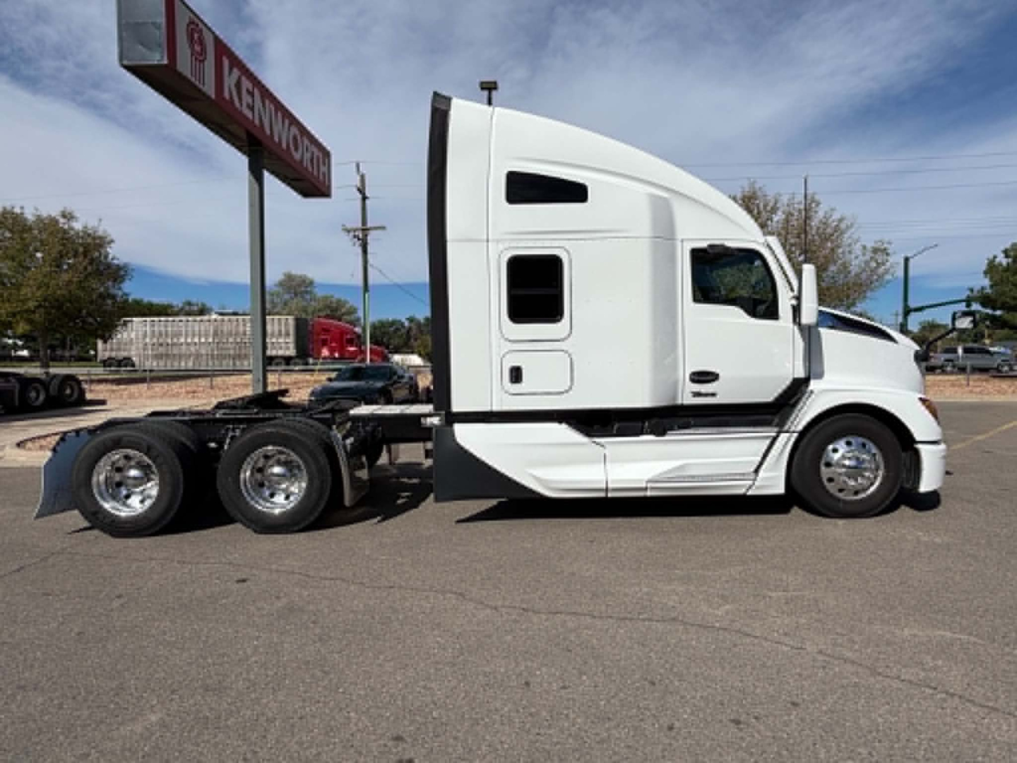 Kenworth T680 conventional sleeper truck side view showing white cab and triple rear axles.