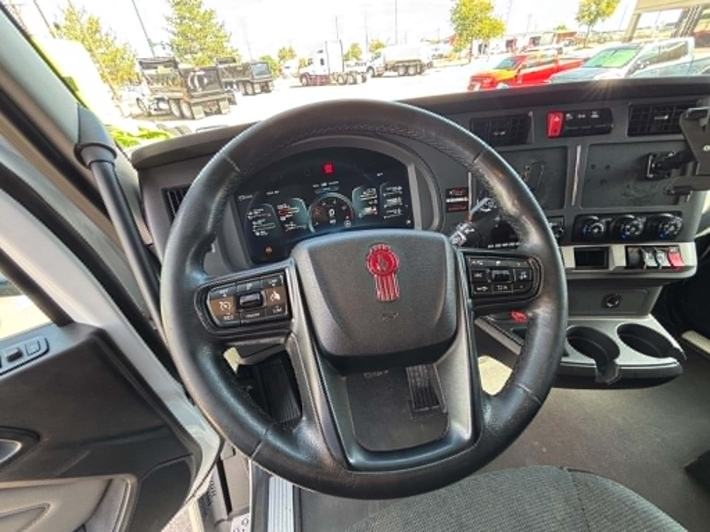 Steering wheel and dashboard of a 2023 Kenworth T680 truck cab interior with instrument cluster and controls.