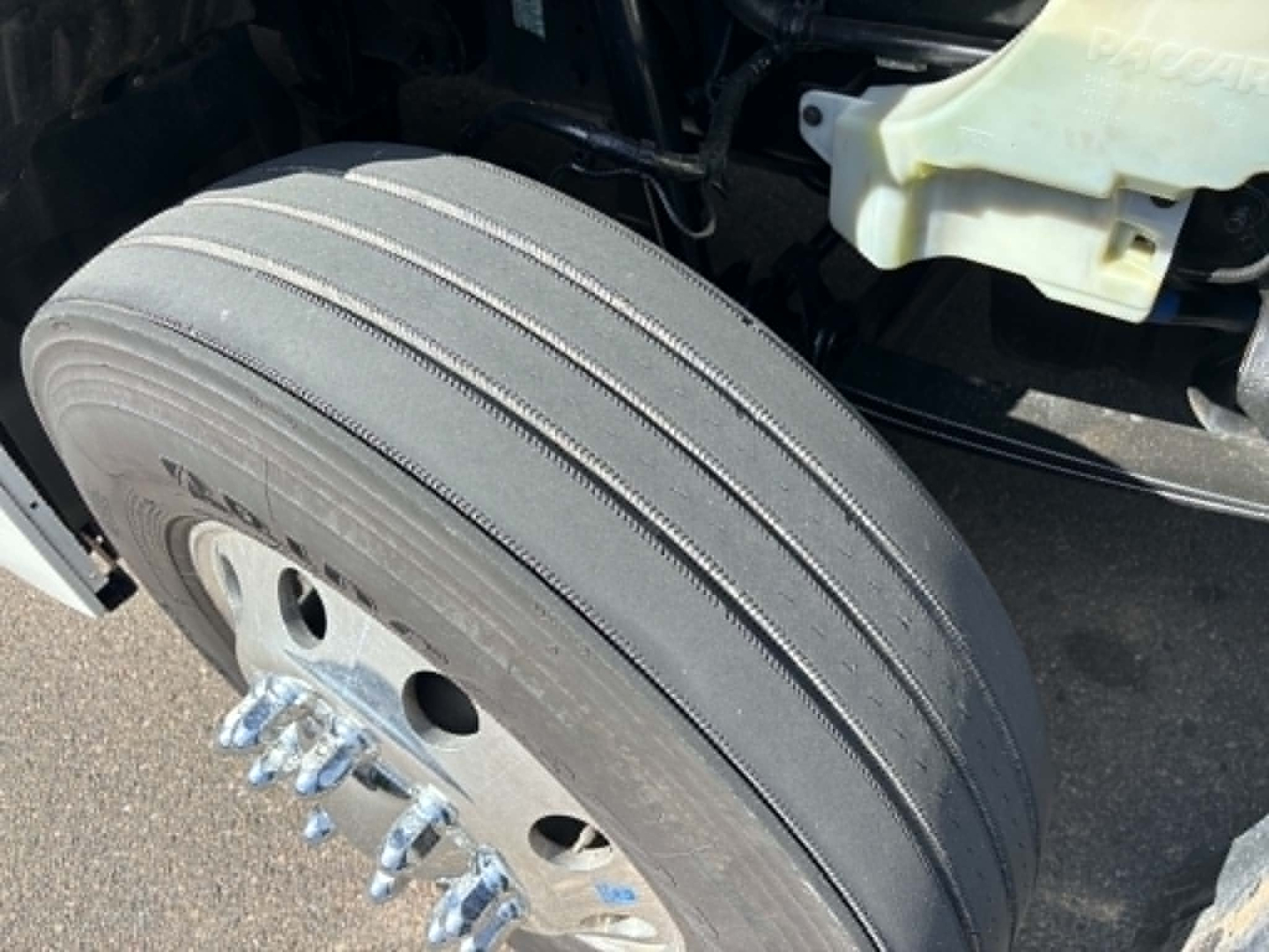 Kenworth T680 wheel/tire and front fender area showing tire tread with multi-rib design and wheel studs.