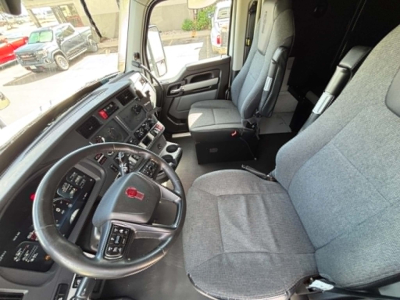 Cab interior of a 2023 Kenworth T680 showing steering wheel, driver's seat, and dashboard in view.