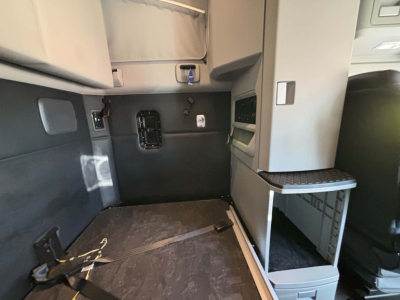 Kenworth T680 cab interior showing sleeper area and side table with storage, cabin controls, and lower panel access.